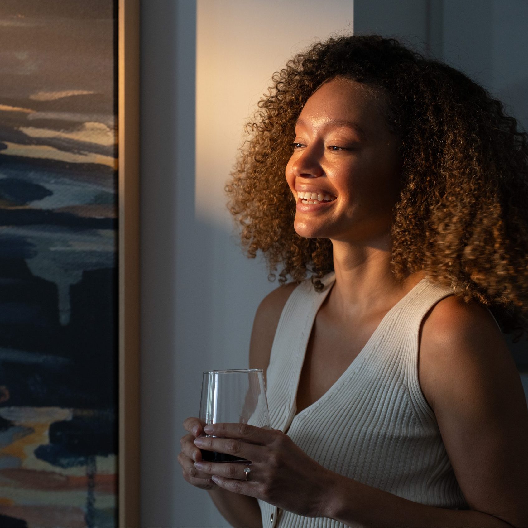 Woman drinking wine in sunset in apartment home